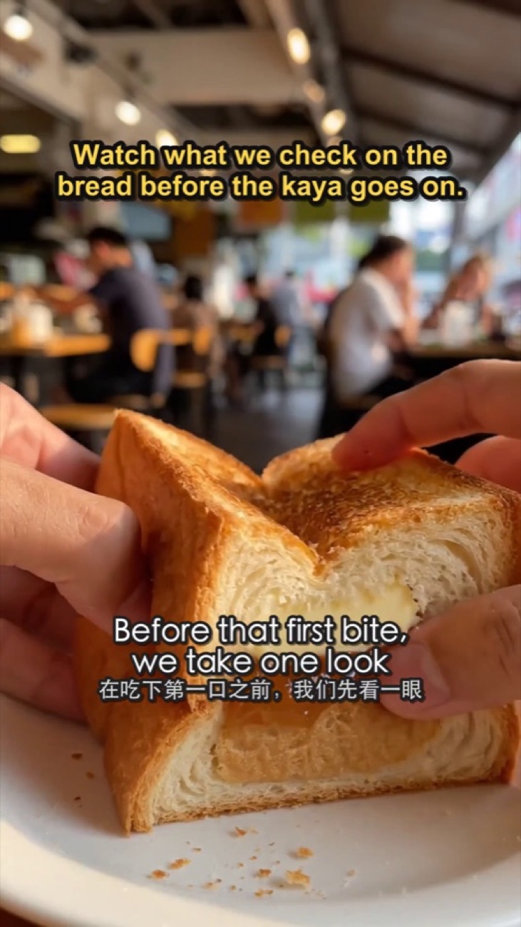 A frame from a finished video: hands pulling apart kaya toast, with a title at the top and a subtitle across the middle.